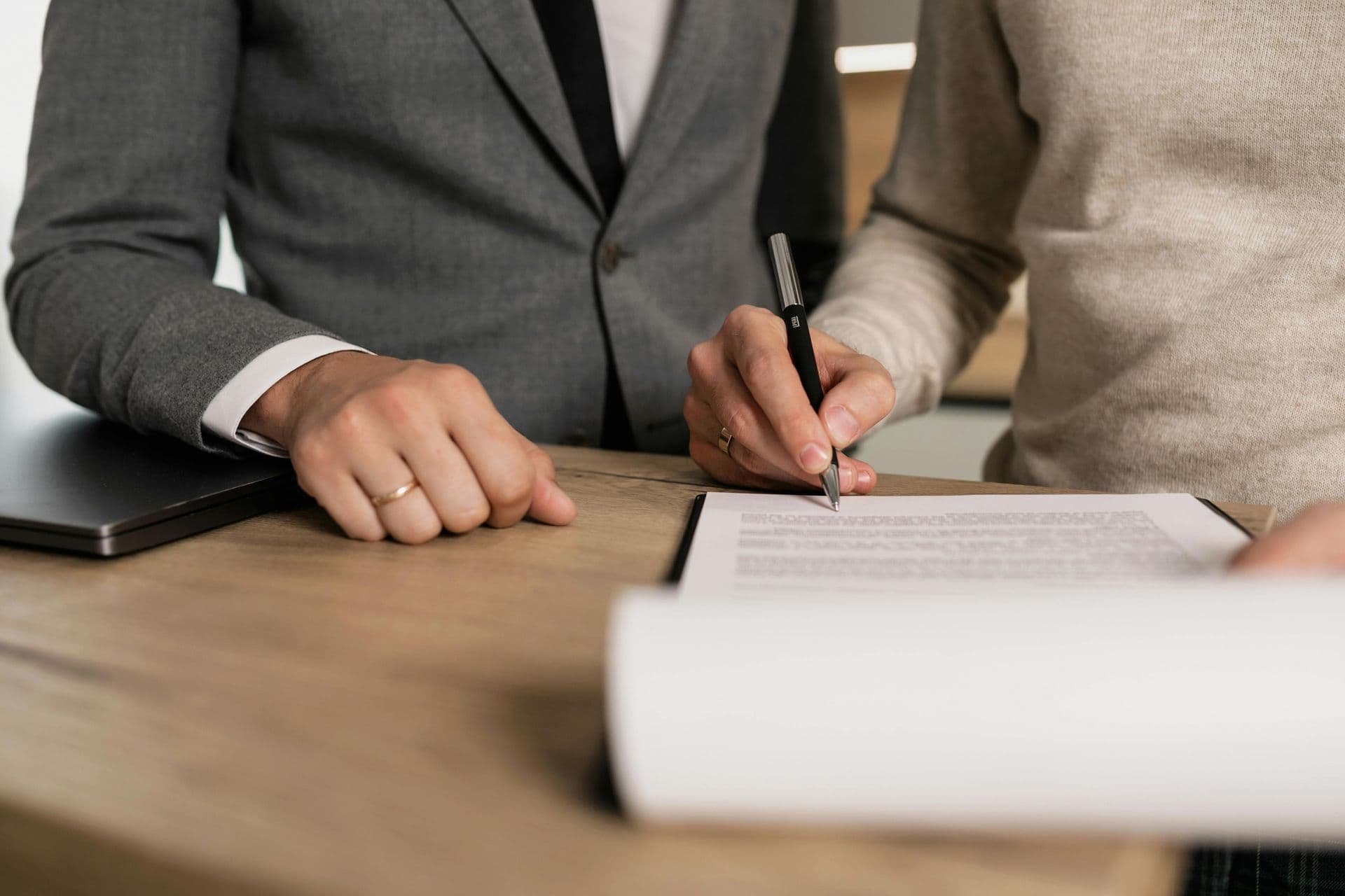 Un hombre y una mujer están sentados en una mesa firmando un documento.